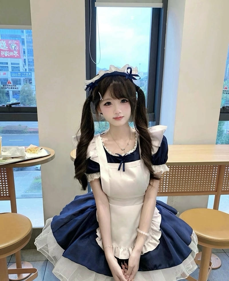 Gái xinh mặc đồ hầu gái tạo dáng bên bàn gỗ cổ điển